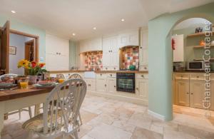 洛尔斯劳特Mill Stream Cottage的厨房配有白色橱柜和桌椅