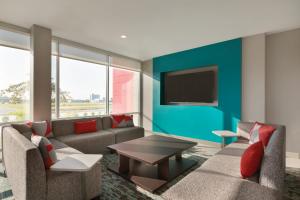德斯普兰斯avid hotels - Chicago O Hare - Des Plaines的客厅配有沙发和墙上的电视