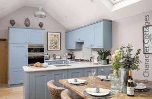 斯托昂泽沃尔德Lavender Cottage Stow-on-the-Wold的厨房配有蓝色橱柜和木桌