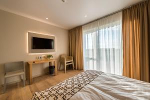 UzvaraHotel Miķelis的酒店客房配有一张床、一张书桌和一台电视。
