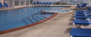 比韦罗拉斯希蕾娜斯酒店的大楼内带蓝色椅子的大型游泳池