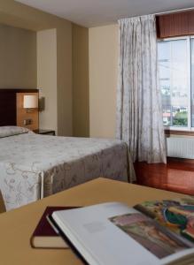 拉科鲁尼亚Apartamentos Portazgo的酒店客房设有两张床和一张桌子,并备有书籍