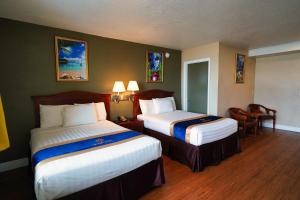 代托纳海滩Sandals Inn的酒店客房带两张床和一张桌子以及椅子。