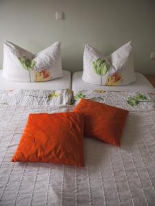 莱茵河畔洛尔希罗斯勒酒庄酒店的两张床,上面有橙色枕头