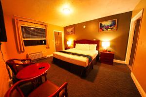 代托纳海滩Sandals Inn的酒店客房带一张床、一张桌子和椅子