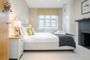温莎Castle Properties:Eton-The College的一间白色卧室,配有一张床和一个壁炉