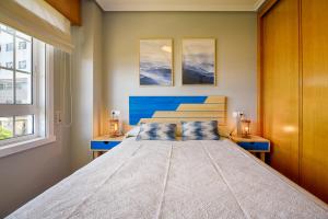 拉科鲁尼亚San Amaro Beach 3 by TheBlueWaveApartments com的一间卧室设有一张大床和两个窗户。