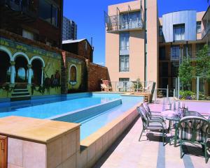 墨尔本Melbourne Metropole Central Official的一座带桌椅的游泳池位于酒店大楼旁