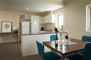珀斯Baileys Serviced Apartments的厨房以及带桌子和蓝色椅子的用餐室。