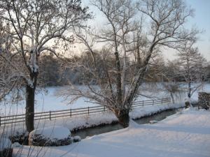 奥登河畔的布雷特维尔Maison de vacances _ Le Bas Manoir的雪覆盖的栅栏,靠近一些树