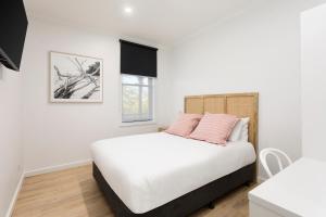 拜恩斯代尔Grand Terminus Hotel的卧室配有白色床和粉红色枕头