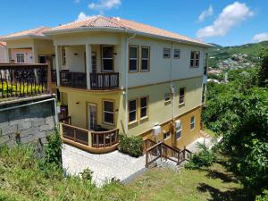 格罗斯岛Keep Cool Guesthouse的山丘上带阳台的黄色房子