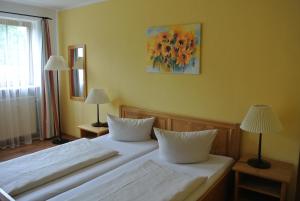林德伯格紫薇斯洛德豪斯酒店的卧室内的两张床,配有两盏灯和墙上的绘画