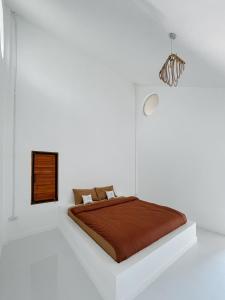 拜县拜县艾特尔别墅的白色卧室,配有一张带棕色毯子的床