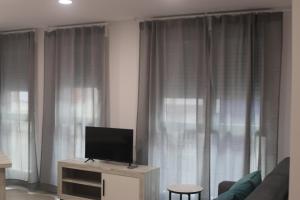 佩尼斯科拉APARTAMENTOS AGUAMARINA的客厅配有木柜上的平面电视