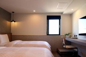 员林康桥商旅 - 员林馆 的一间卧室设有两张床、一张桌子和一个窗口。