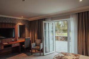 安特里姆Dunadry Hotel And Gardens的酒店客房设有一张书桌、一台电视和滑动玻璃门