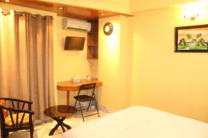 达卡Maple Crest Service Apartment的一间卧室配有一张床、一张桌子和一张书桌