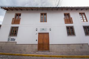 库斯科7th Wonder Apart Hotel Cusco的白色的建筑,设有棕色的门和窗户