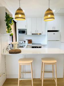 楠巴卡黑兹THE DAVEY Luxury home的厨房配有白色橱柜和2张凳子