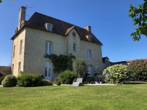 梅尔维尔弗朗瑟维尔普拉格Domaine "Les Bois Flottes" dans Maison de Charme au bord de mer et proche de Cabourg的一座带草地庭院的大型石屋