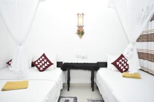 锡吉里亚斯吉利岩石边民宿的配有2张床的带白色窗帘和桌子的客房