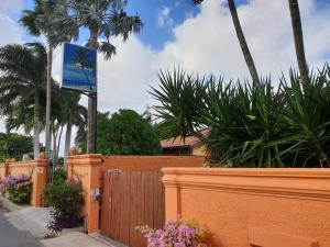 巴亚希贝PLAYA BLANCA BED AND BREAKFAST的棕榈树和鲜花围栏上的标志
