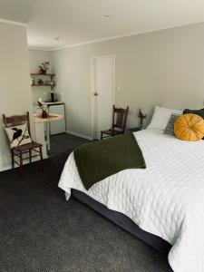 怀托摩洞穴Aranui Farmstay的卧室配有一张白色大床和两把椅子