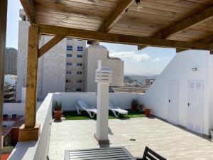 大加那利岛拉斯帕尔马斯Holiday Home & Rooftop Lounge的一个带木屋顶的庭院,上面摆放着两把椅子
