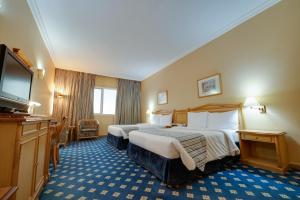 阿布扎比Grand Continental Hotel的酒店客房设有两张床和一台平面电视。