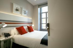 圣塞瓦斯蒂安Legazpi Doce Rooms & Suites的卧室配有白色的床、红色枕头和窗户