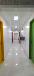 卡波布里奥Guest House Renascer K&W的一条空的走廊,设有绿门和白色瓷砖地板