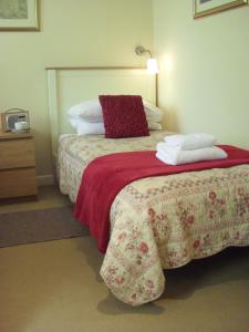滨海韦斯顿机车棚住宿加早餐旅馆的一间卧室配有一张带红色毯子和枕头的床。