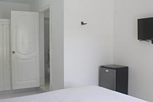 蓬塔卡纳Sweet Home Punta Cana Guest House - VILLA Q15A的一间卧室配有一张床,墙上配有电视