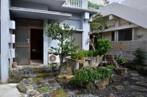 石垣岛Homa Ishigakijima no Yado - Vacation STAY 80173的前面有树和岩石的房子