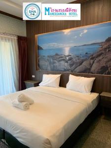 Sangkhaโรงแรมมณีสังขะ的酒店客房的墙上设有一张带绘画的床铺。