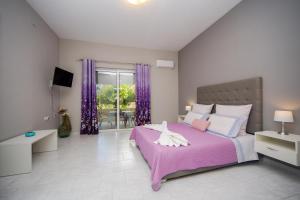阿彻奇洛斯Sunset Apartments的一间卧室配有粉红色的床和紫色窗帘