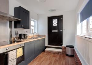 达宁顿堡Donington Cottage Apt 8的厨房设有黑色的门,铺有木地板