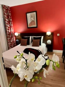 格勒诺布尔格勒诺布尔阿乐皮斯普公寓式酒店的一间卧室配有一张红色墙壁和白色鲜花的床