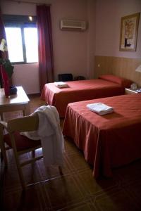 阿尔沃洛特拉斯特拉萨斯酒店的酒店客房带两张床和一张桌子以及椅子。