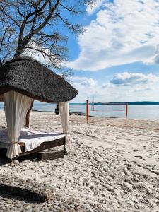 佩列亚斯拉夫-赫梅利尼茨基Secret Resort Club的海滩上的一张带草伞的床