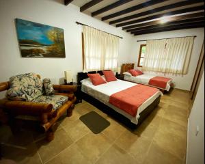 ChinchináCasa Chute的一间卧室配有两张床、一张沙发和一把椅子