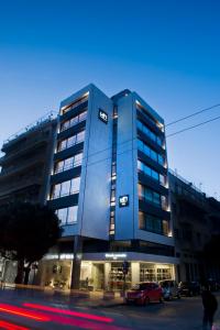 雅典NLH FIX | 街区生活方式酒店的一座蓝色的建筑,前面有汽车停放