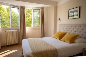 佩皮尼昂蒙蒂阿尔酒店的一间卧室设有一张床和两个窗户。