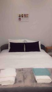 普里什蒂纳ORA-PRN,cosy apartment in the city center的一张带黑色枕头的白色床和毛巾