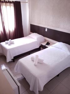 伊瓜苏Hotel Castelo Branco的酒店客房,配有两张带白色床单的床