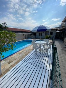 弗洛里亚诺波利斯Excelente casa com piscina na Praia de Ingleses的池畔甲板配有桌椅