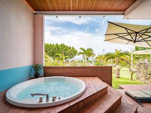 石垣岛ザ・ビーチテラスホテルアオ石垣的庭院内的按摩浴缸和遮阳伞