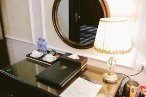 下龙湾Vincent Halong Hotel的一张带台灯、书籍和镜子的桌子