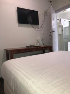 墨尔本Evancourt Motel Malvern East的酒店客房设有一张床和墙上的电视